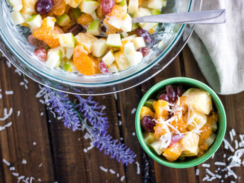 Top view big bowl of Hawaiian Fruit Salad with lavender and shredded coconut sprinkles and a smaller green bowl of fruit salad