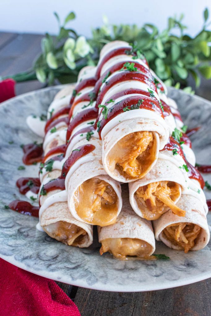Creamy Raspberry Chipotle BBQ Chicken Taquitos, drizzled with ranch, bbq sauce and chopped cilantro, on grey marbled plate. 