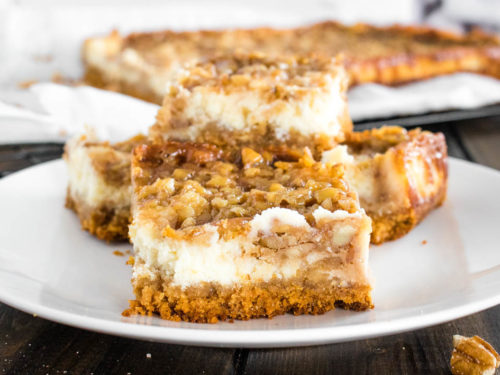 Cut pecan pie cheesecake bars on white plate
