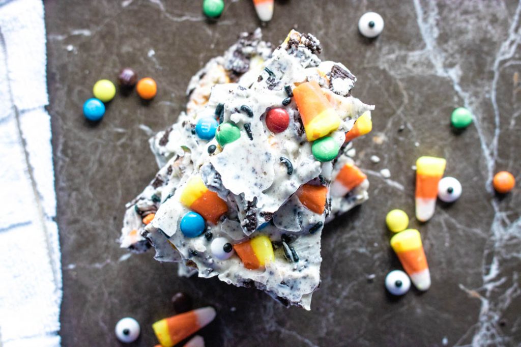 stack of spooky candy bark with loose candies scattered around on table